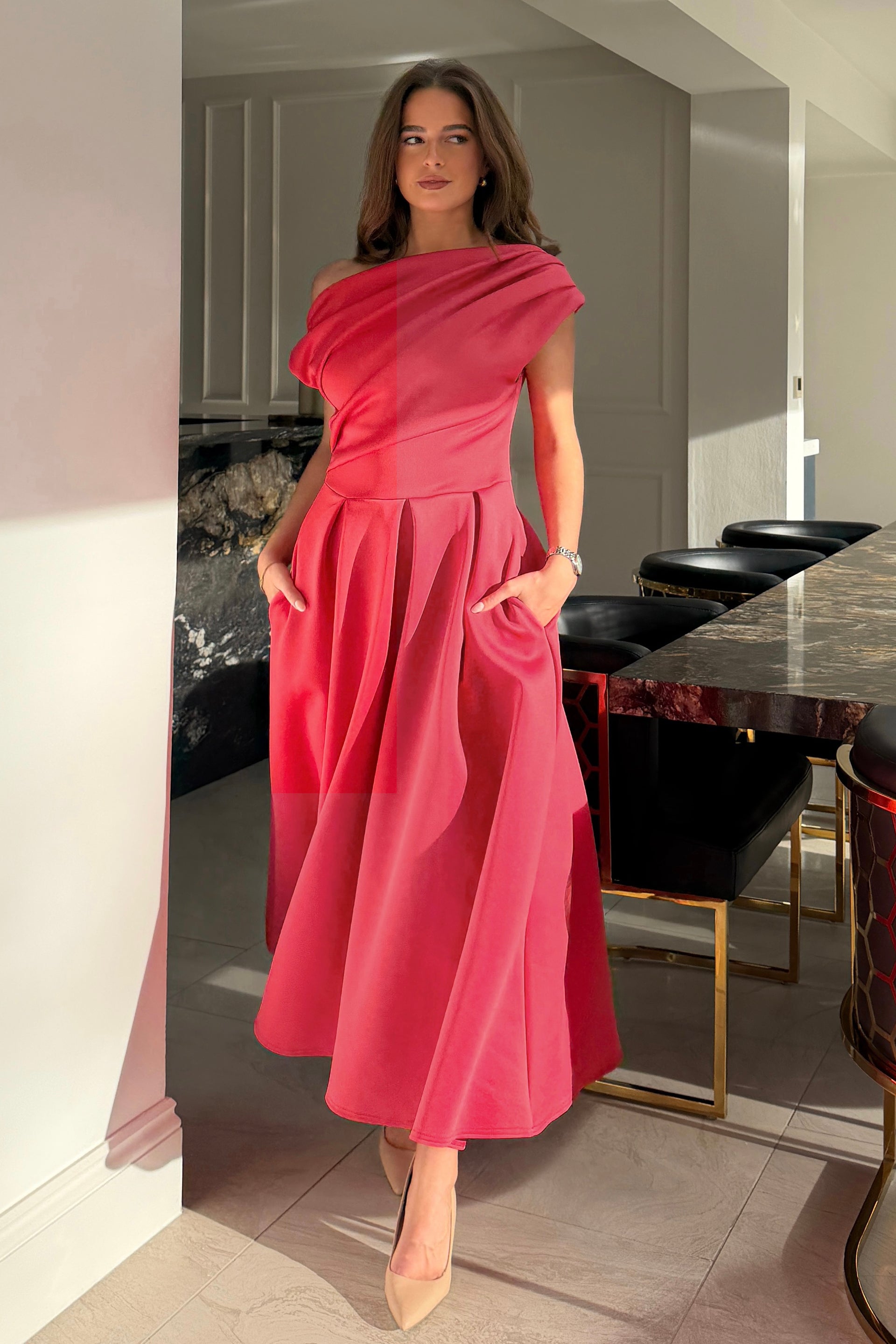 Woman in a pink dress standing in a modern kitchen.