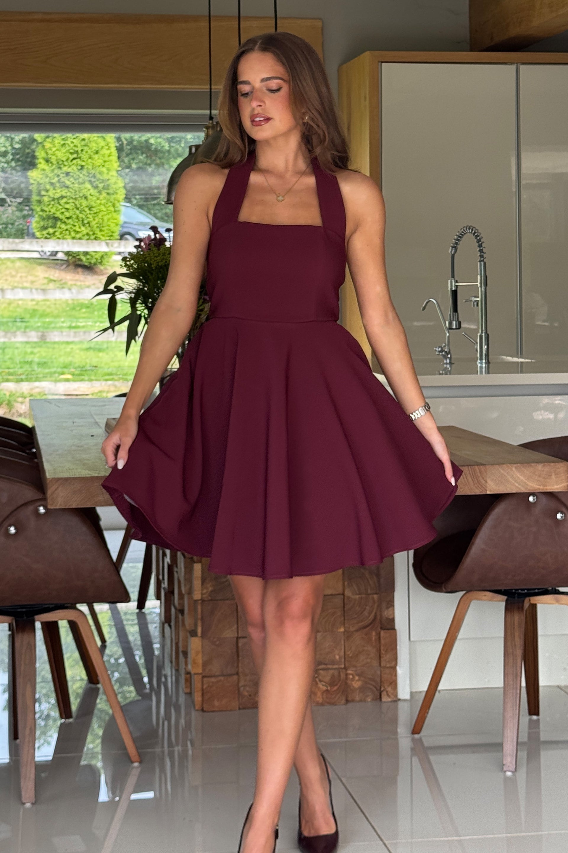 Woman in a burgundy dress standing in a modern kitchen.