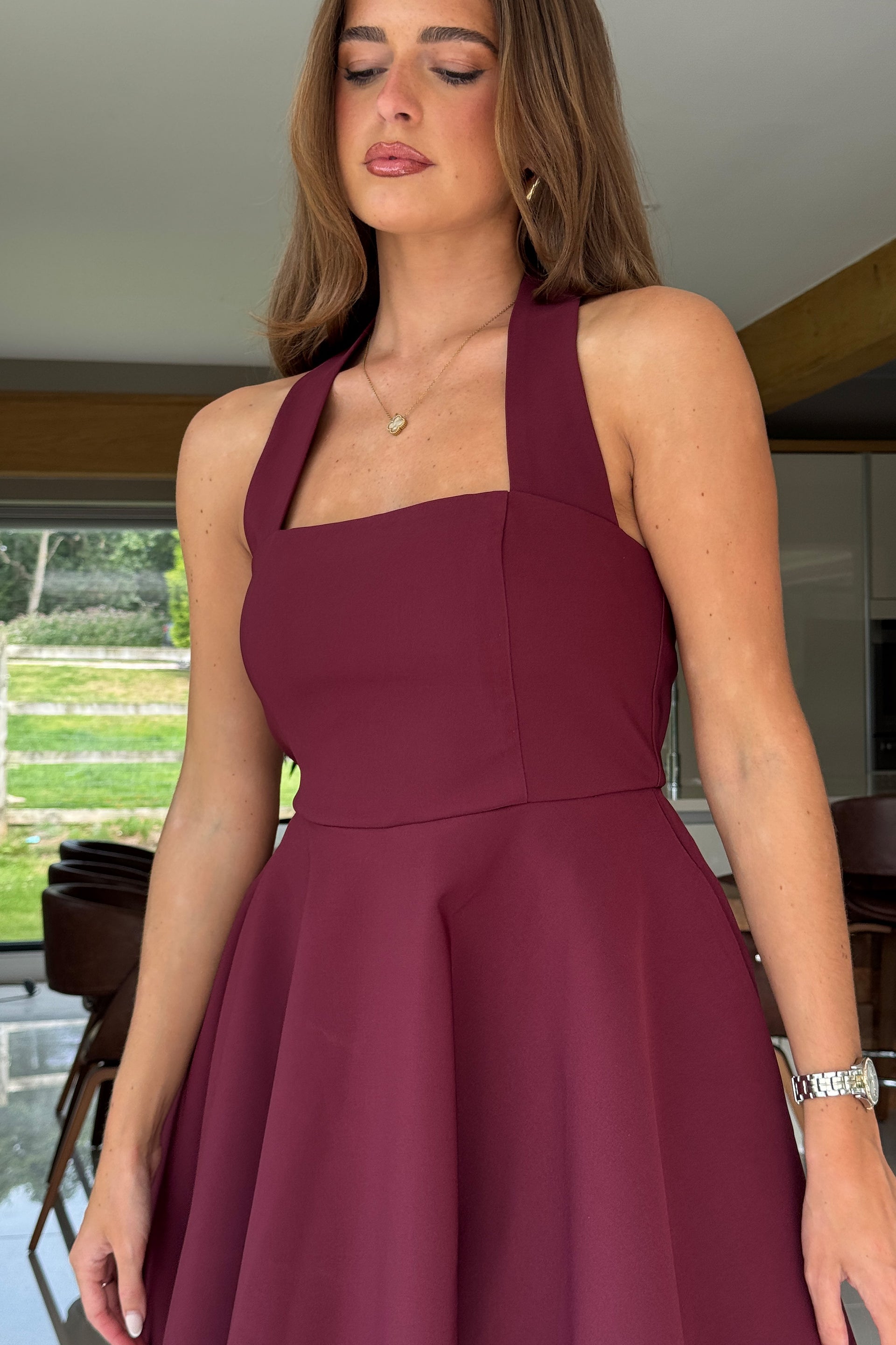 Woman wearing a burgundy dress indoors with a blurred background