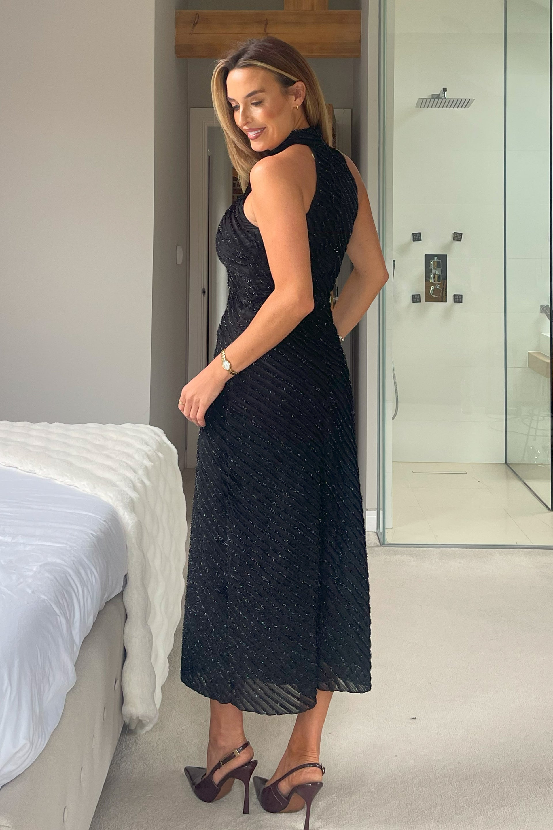 Woman wearing a black dress in a bedroom setting