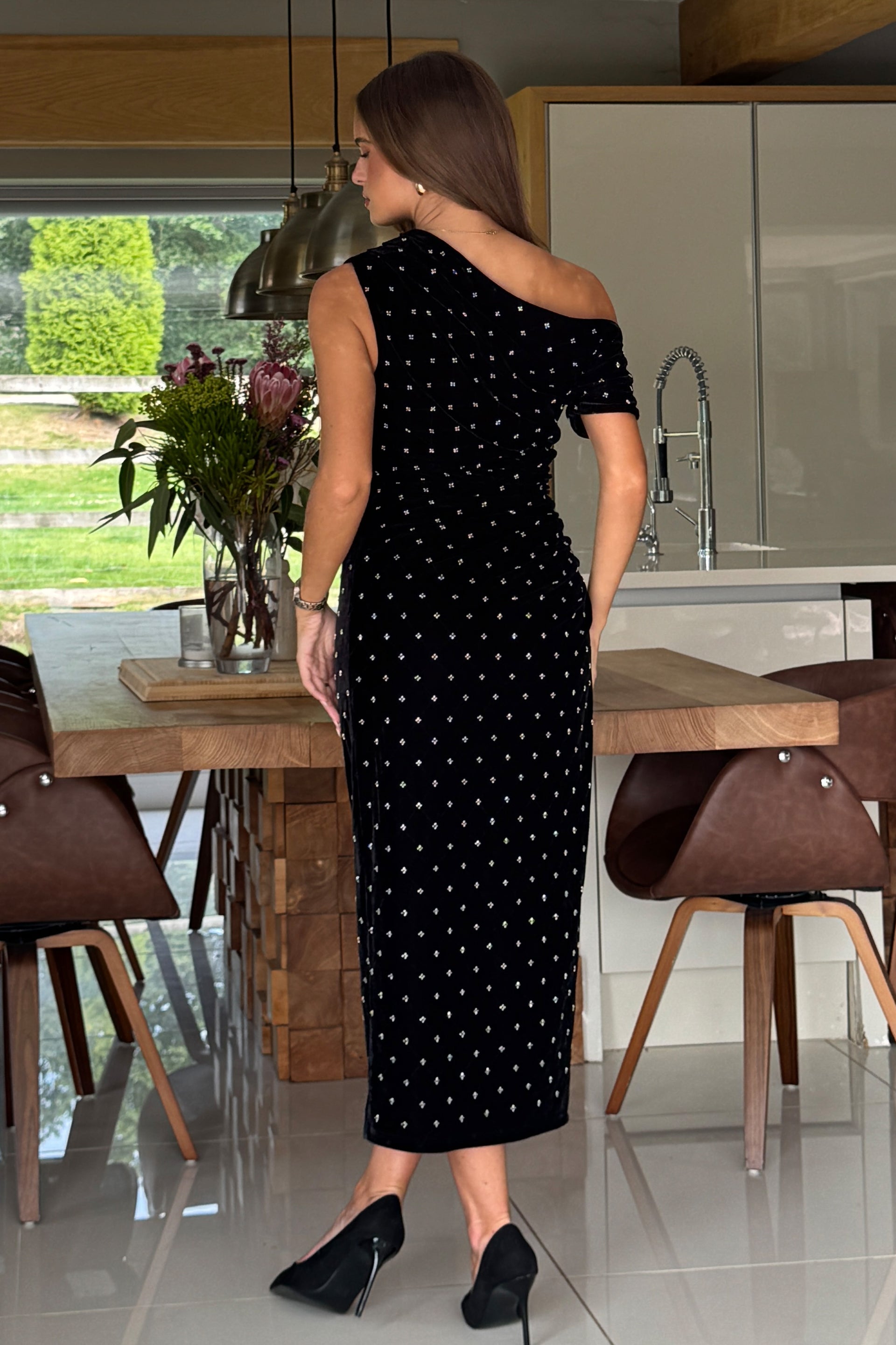 Woman in a black dress standing in a modern kitchen.