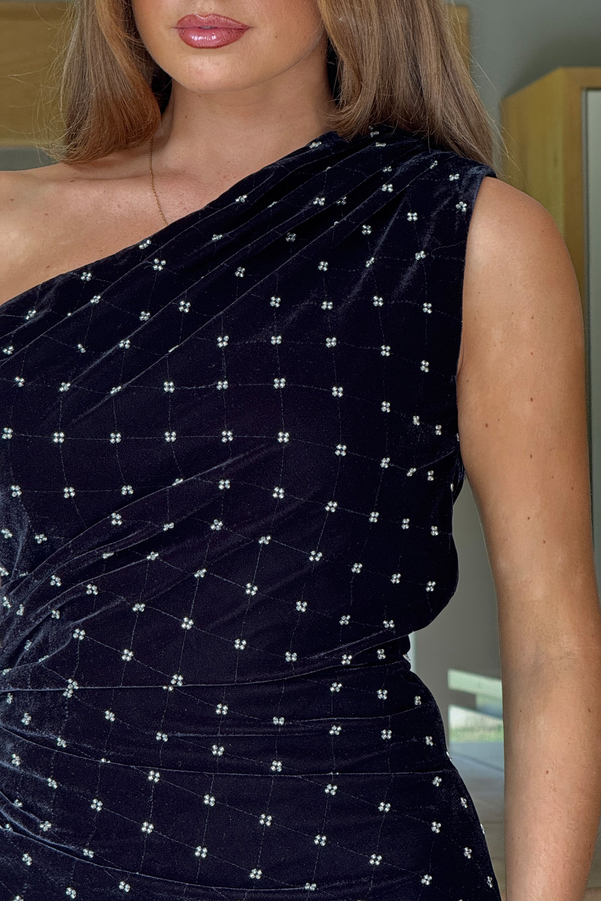 Black one-shoulder dress with white embellishments on a blurred background