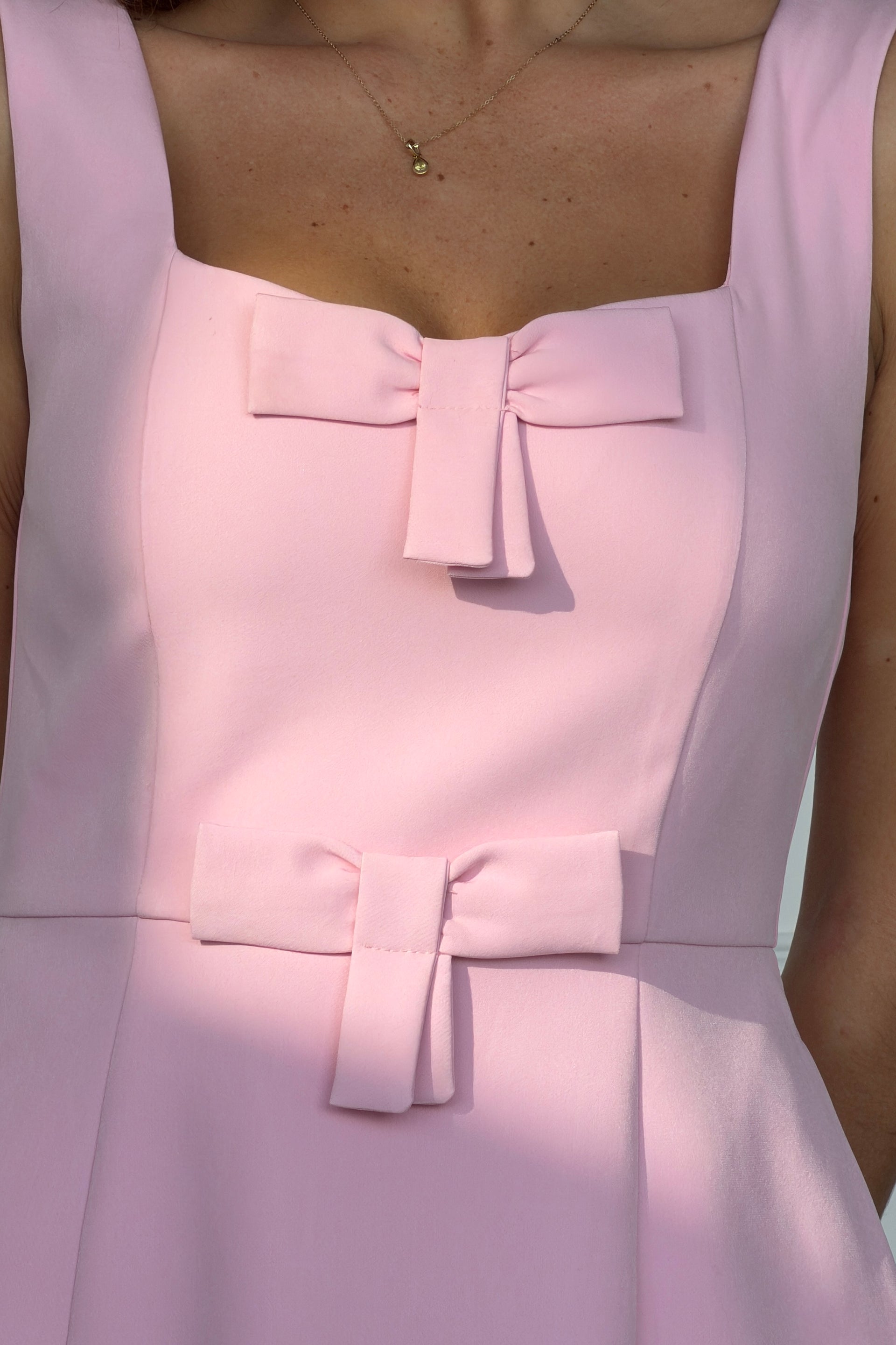 Close-up of a light pink dress with a bow detail on a blurred background