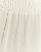 Close-up detail of the white linen trousers fabric