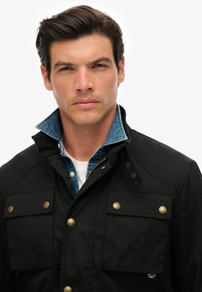 Man wearing a black jacket with a blue collar against a white background