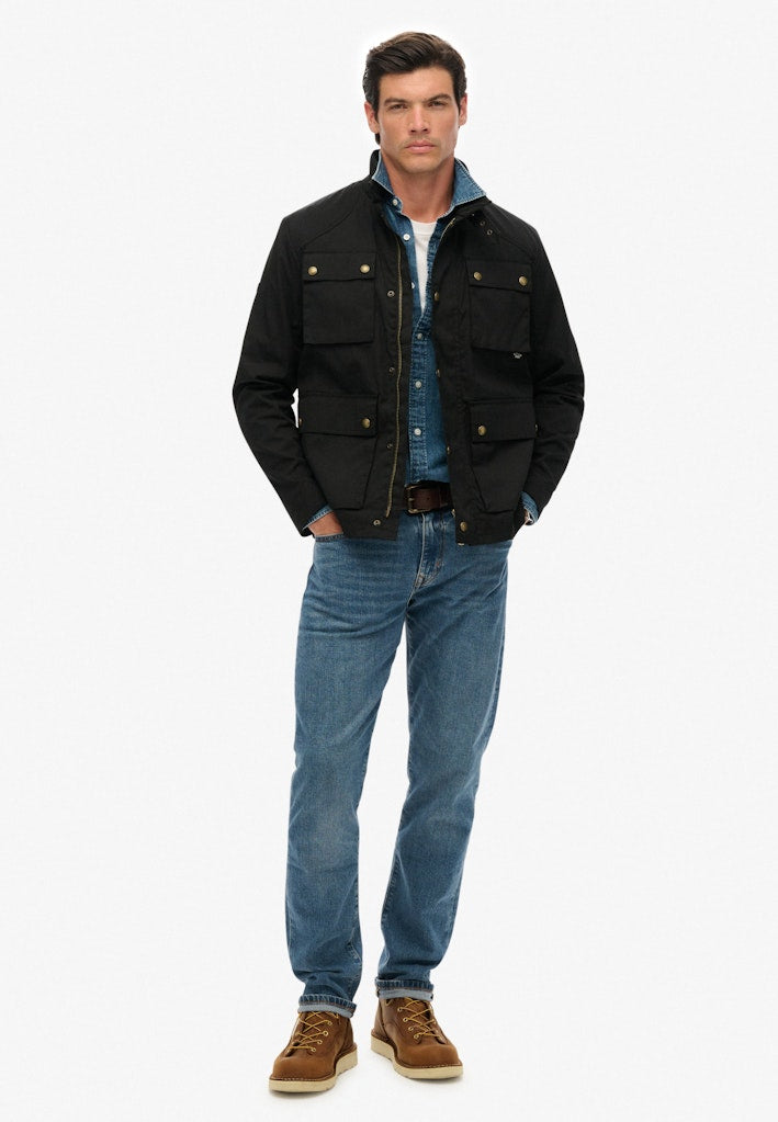 Man wearing a black jacket, blue shirt, and jeans on a white background