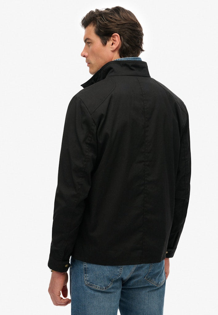 Man wearing a black jacket and blue jeans on a white background