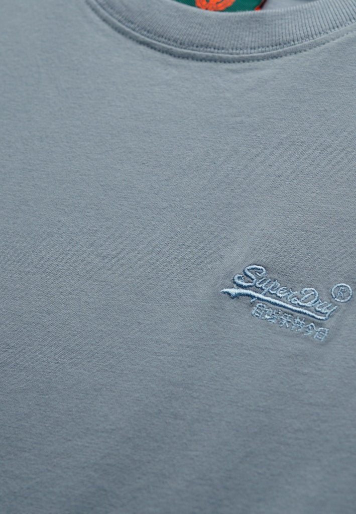 Close-up of a blus t-shirt with a brand logo on a plain background