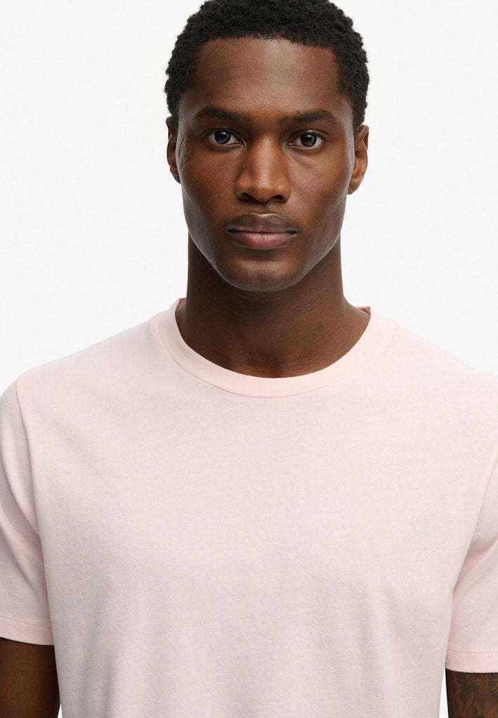 Man wearing a light pink t-shirt against a white background