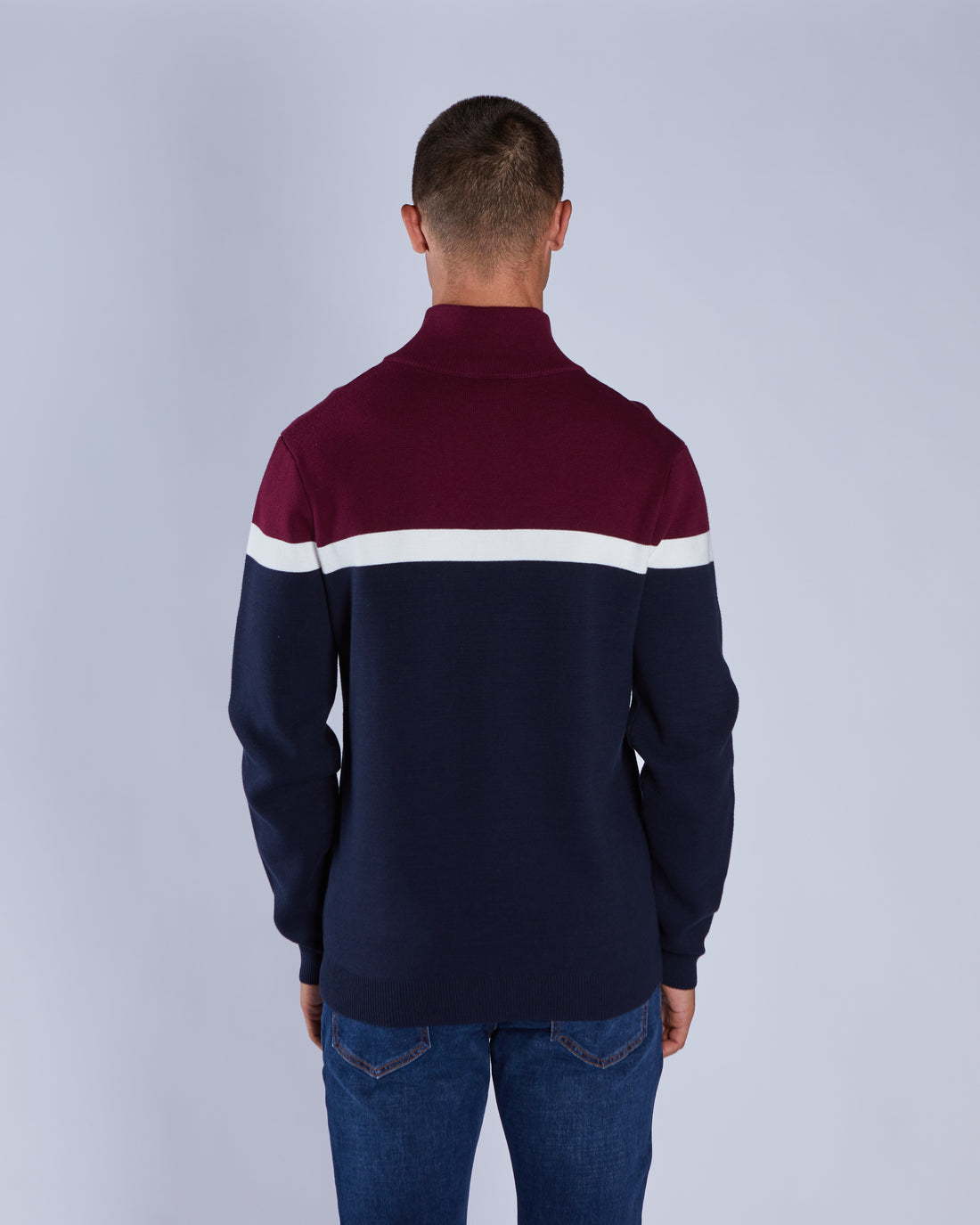 Man wearing a navy and burgundy striped sweater on a light gray background