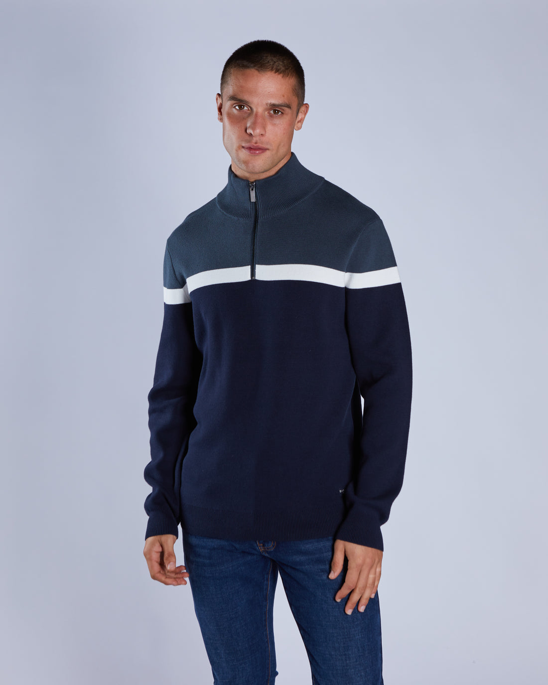 Man wearing a navy blue sweater with a white stripe on a gray background