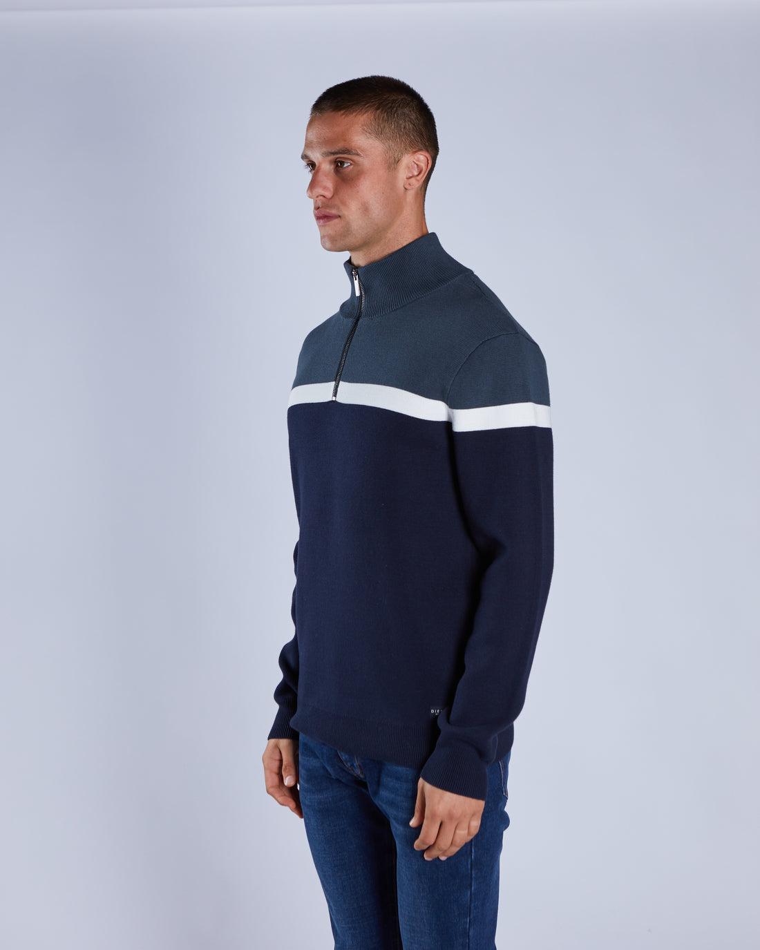 Man wearing a navy blue sweater with a white stripe on a light gray background