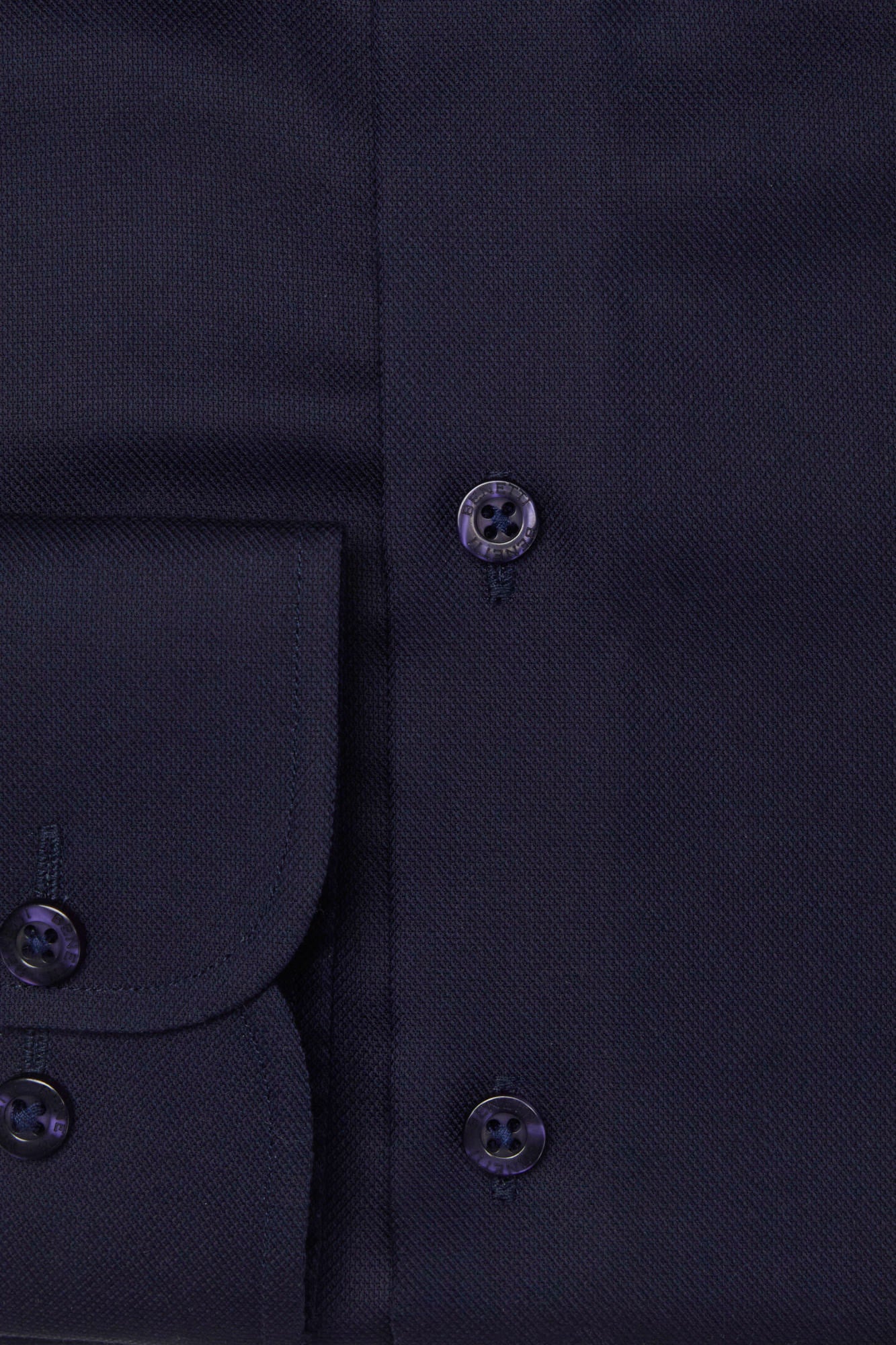 Close-up of a dark blue shirt with buttons on a plain background
