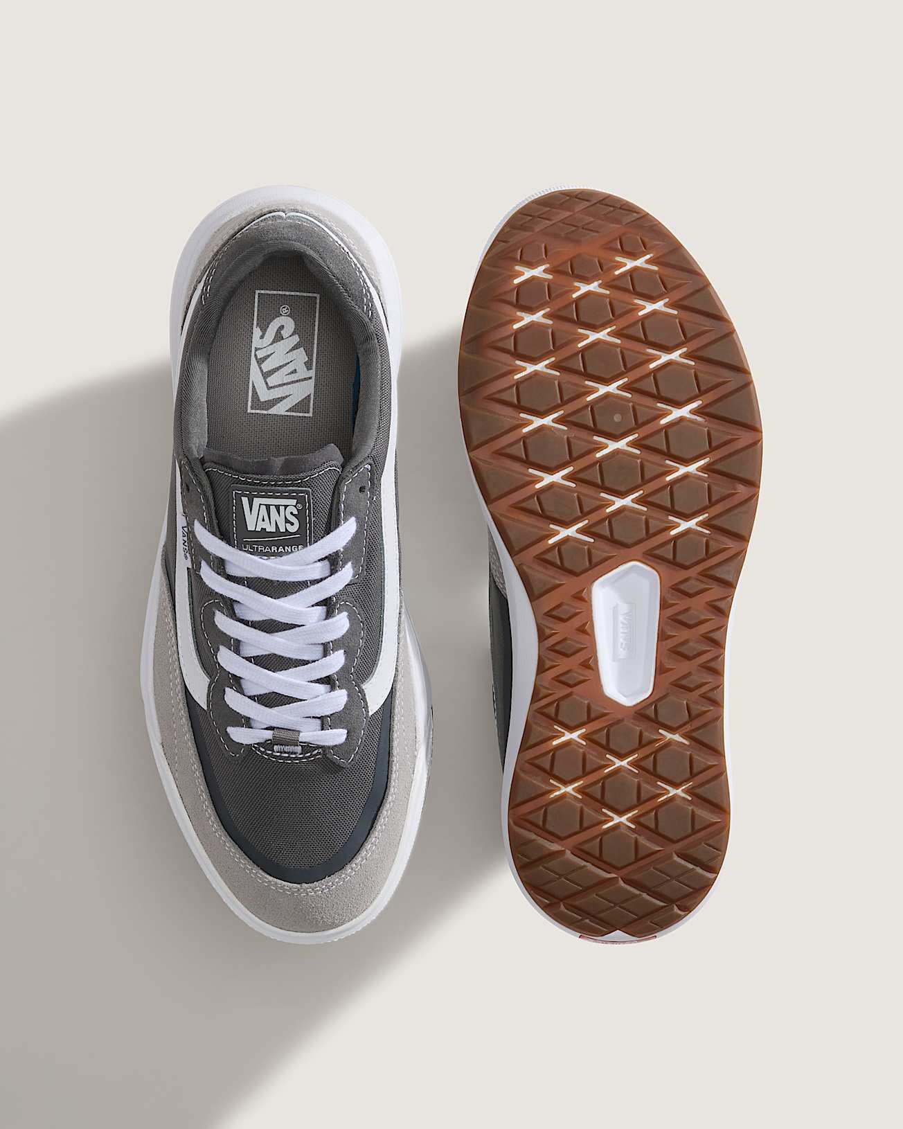 Gray Vans sneaker with white laces and a brown sole on a light gray background