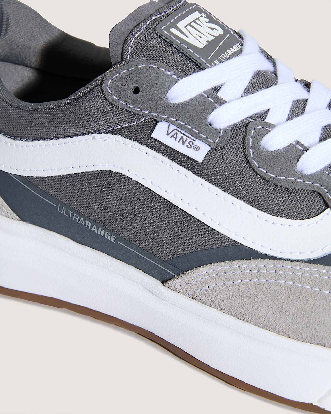 Gray and white Vans sneaker with 'Ultrarange' text on a beige background