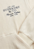 Embroidered logo detail on Superdry Drop Needle Velour Hoodie in Cream