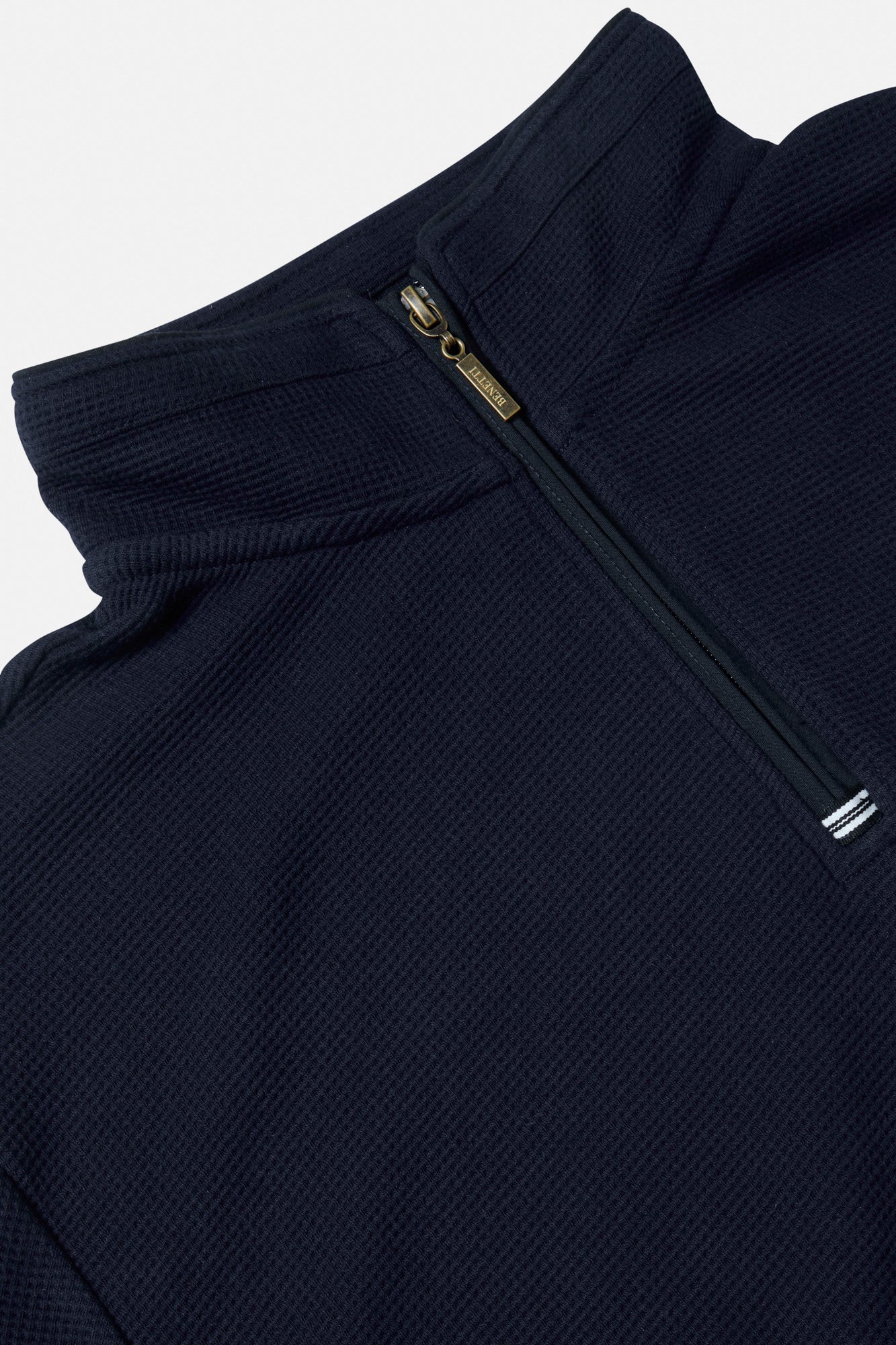 Close-up of a navy blue zip-up garment on a light gray background