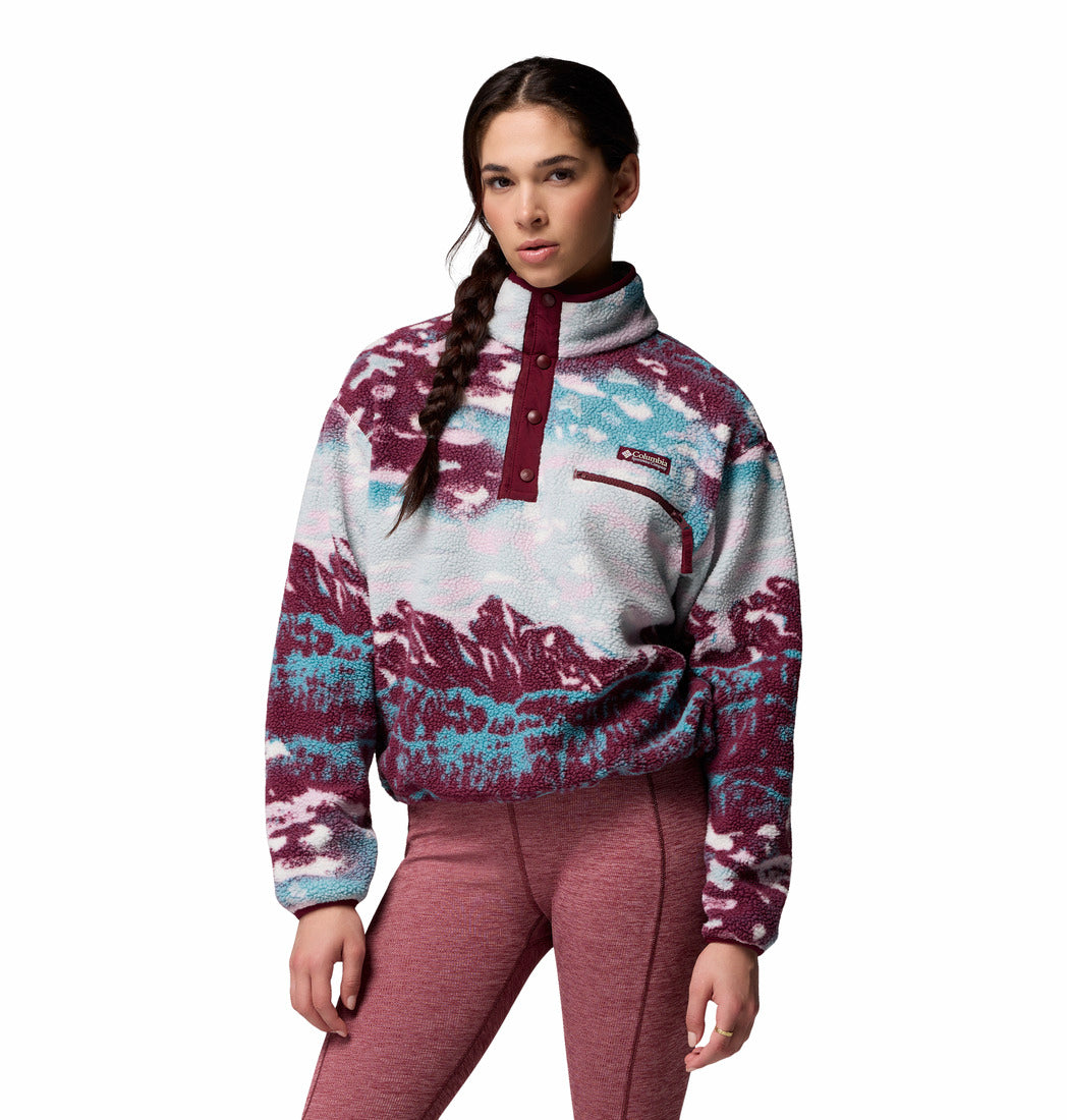 Woman wearing a patterned pullover with a visible brand logo on a white background