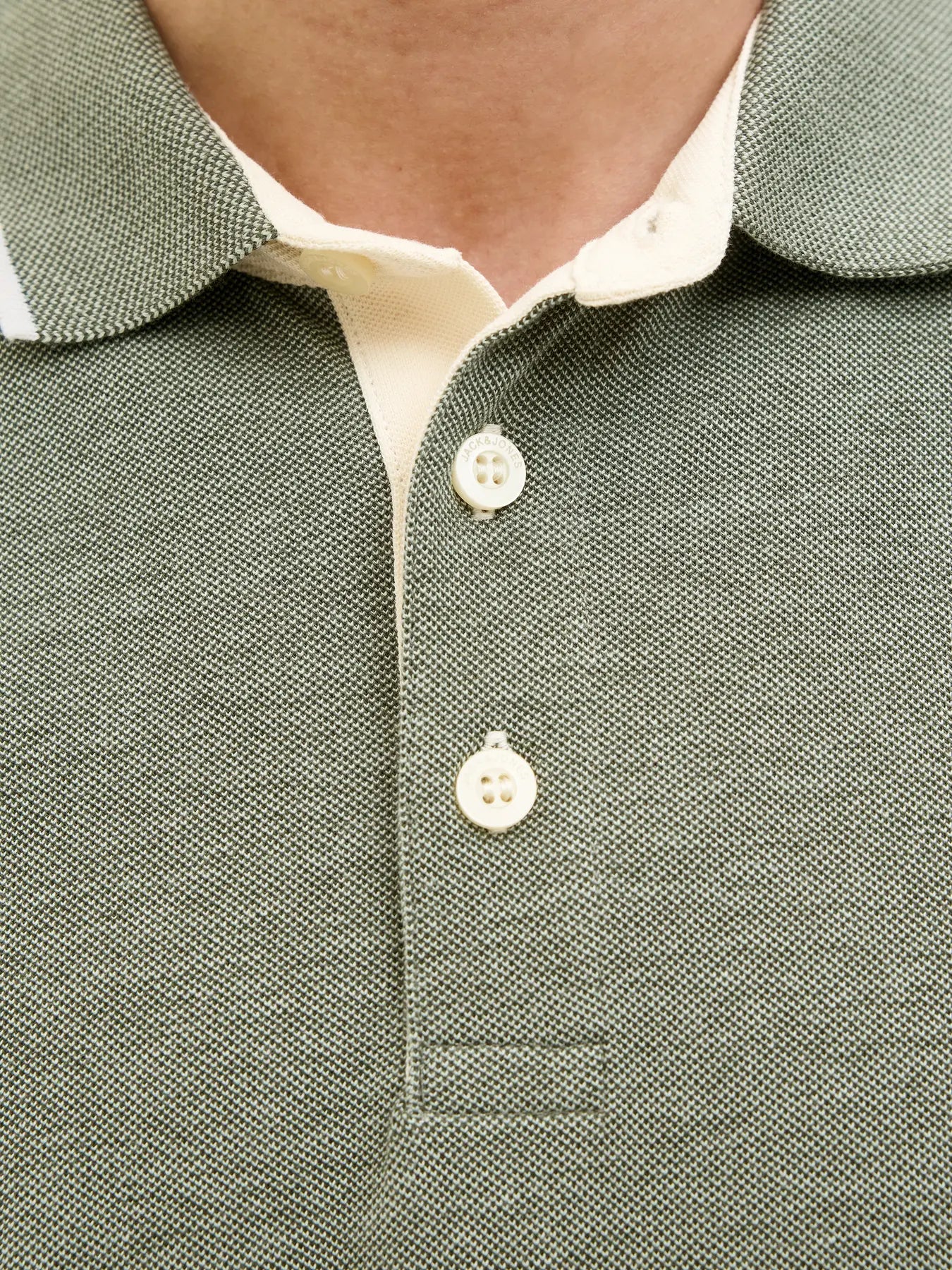 Close-up of a green textured polo shirt with white buttons
