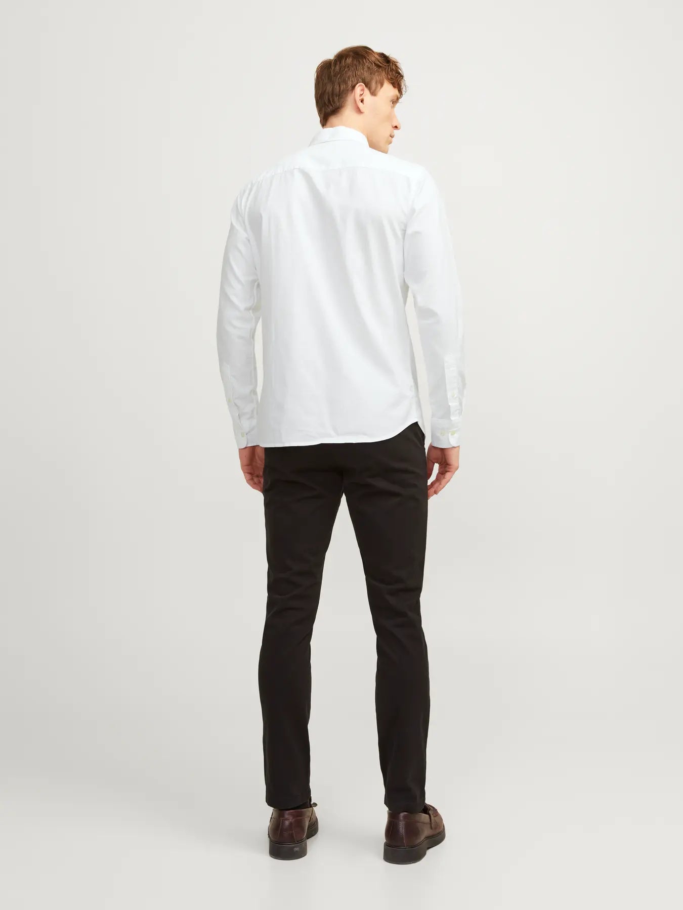 Man wearing a white shirt and black pants on a white background
