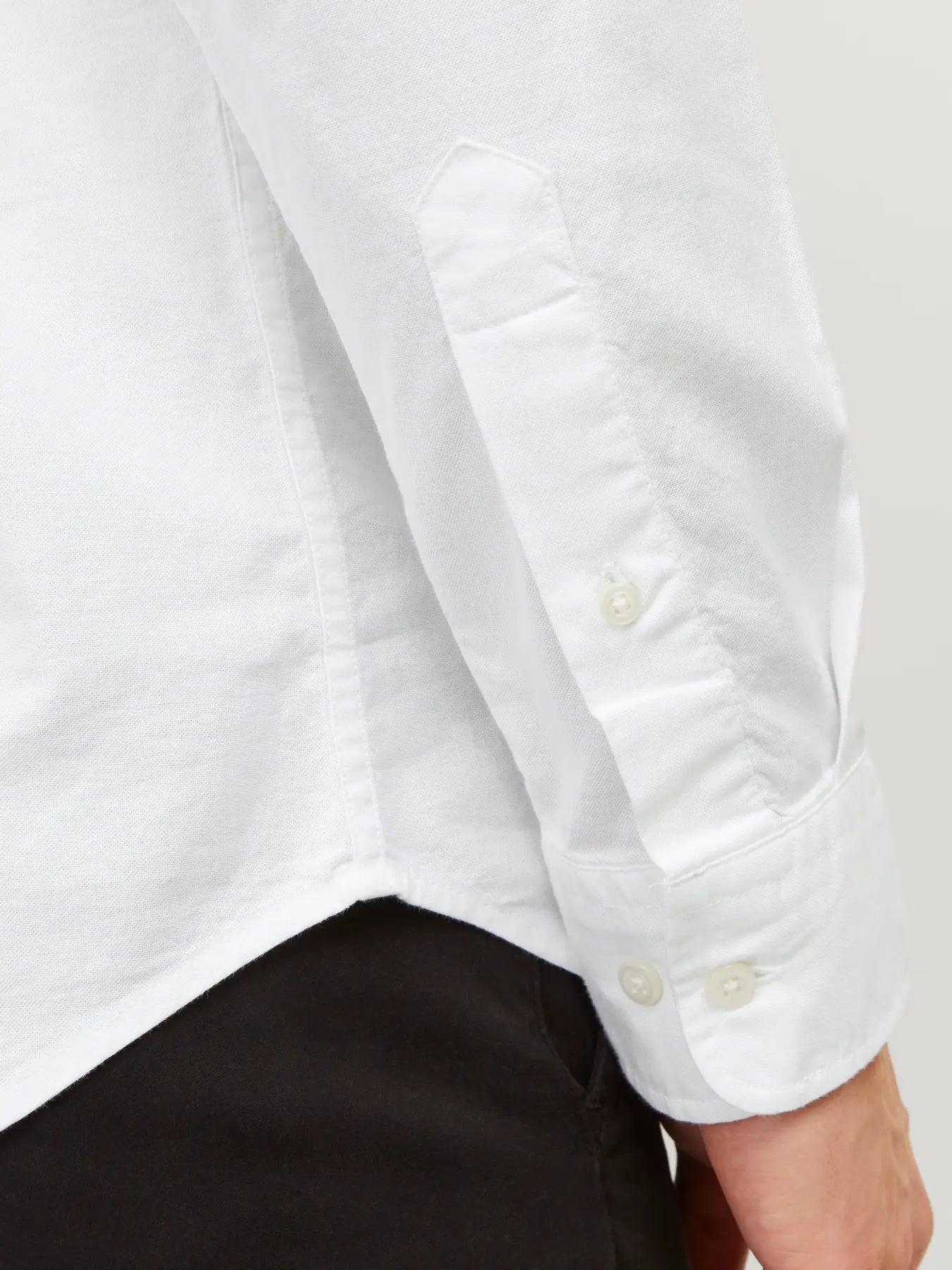 Close-up of a white shirt with rolled-up sleeves on a plain background