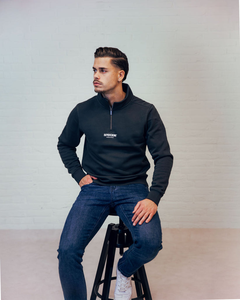 Man wearing a dark green zip up sweatshirt looking right