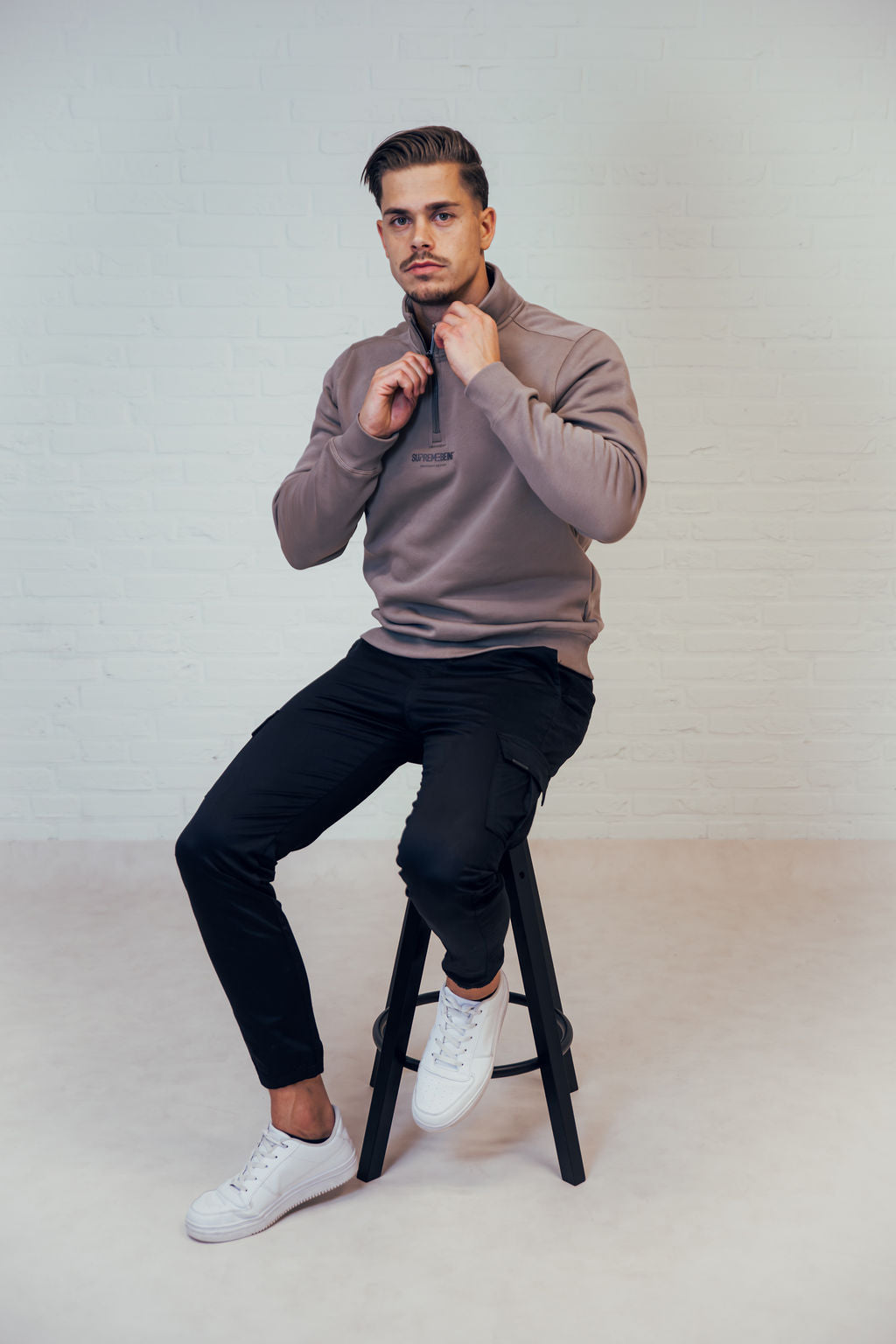 Supreme Being Titan quarter-zip sweatshirt in Taupe worn by seated model, front view