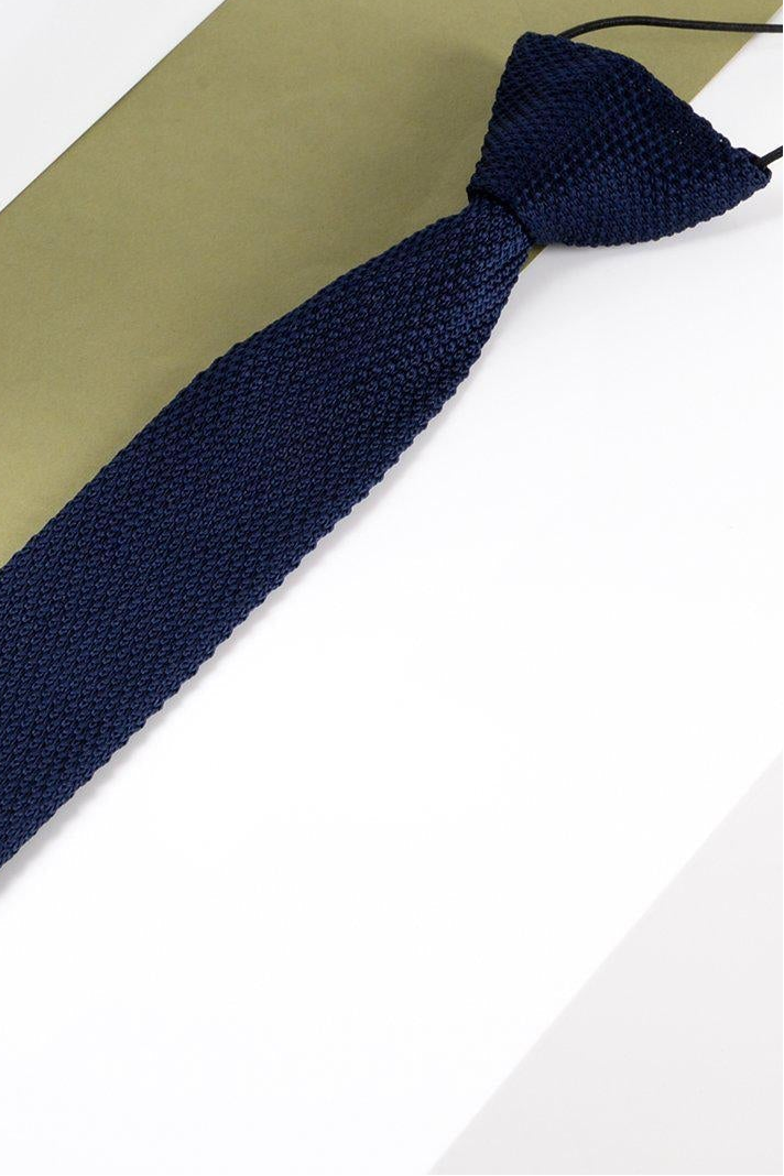 Navy blue kid boy knitted tie on a white and beige background