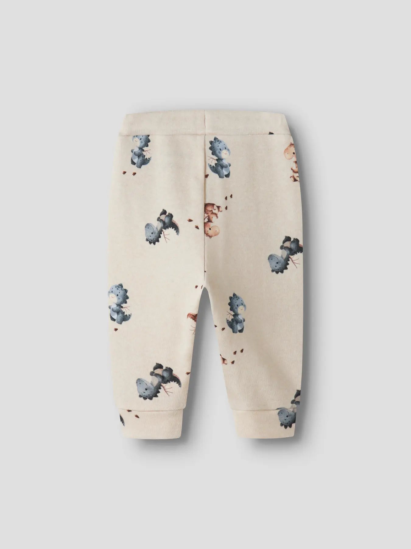 Beige baby pants with dinosaur pattern on a light gray background