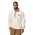 Man wearing a cream-colored fleece pullover with a brand logo on a white background
