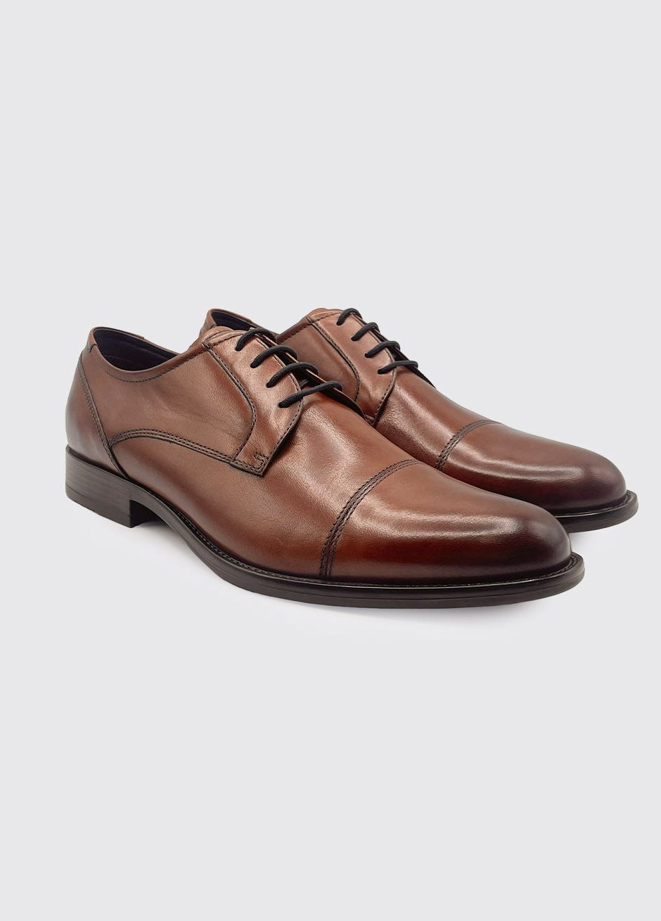 Pair of Derek whiskey brown leather dress shoes on a light gray background