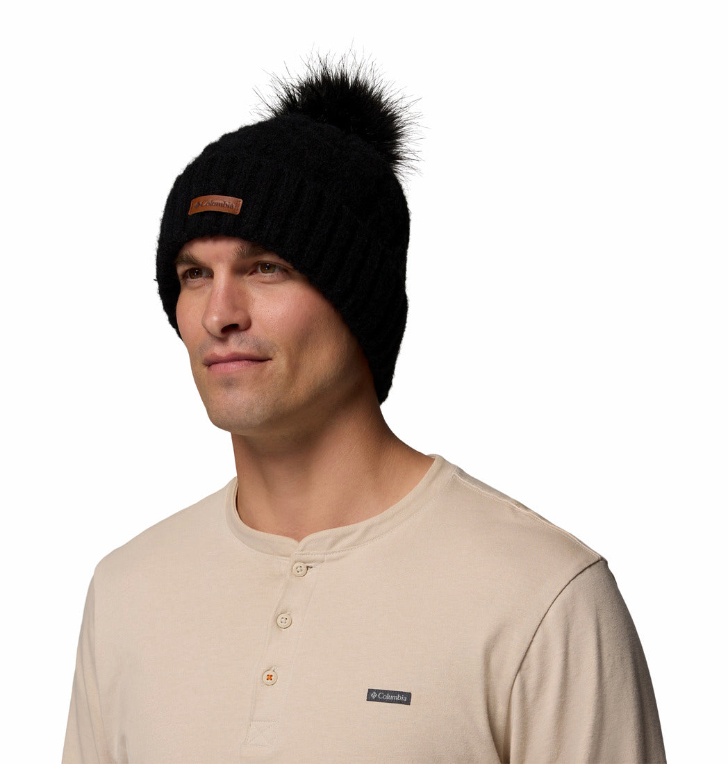 Man wearing a black beanie with a pom-pom on a white background