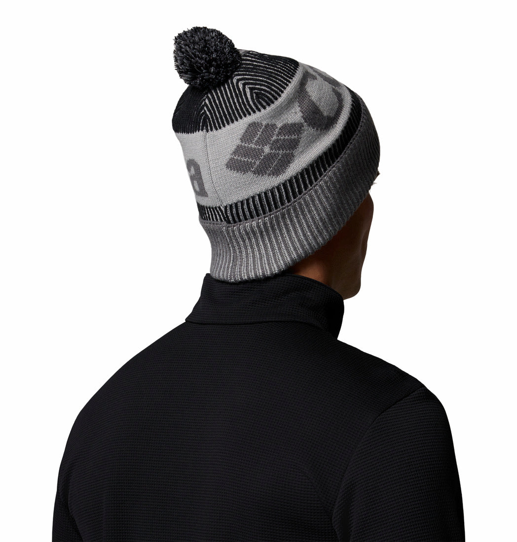 Person wearing a gray and black knit beanie with a pom-pom on a white background