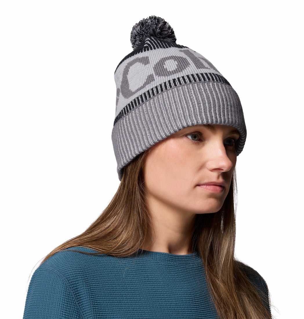 Woman wearing a gray beanie with a brand logo on a white background