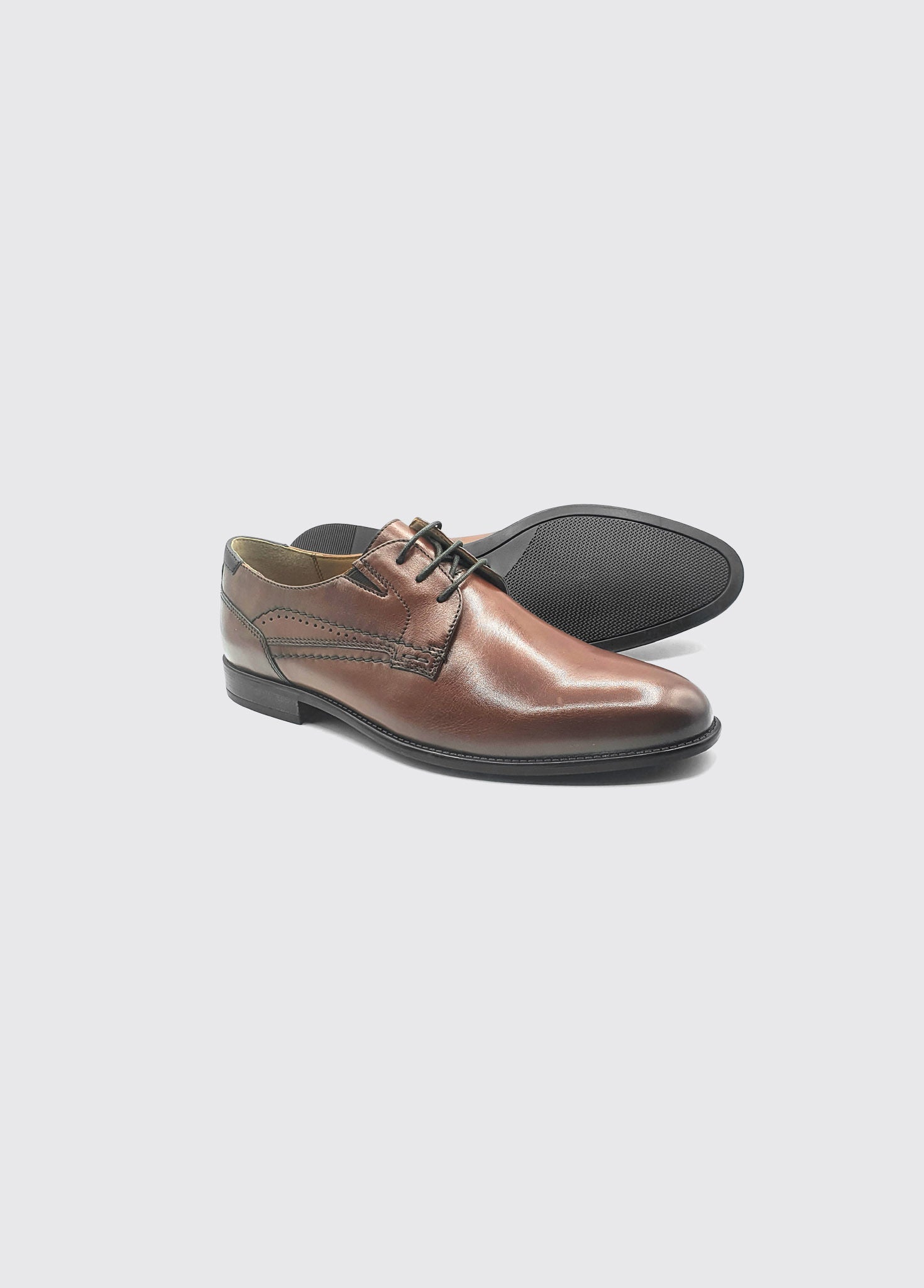 Brown leather shoes on a light gray background with a sole view