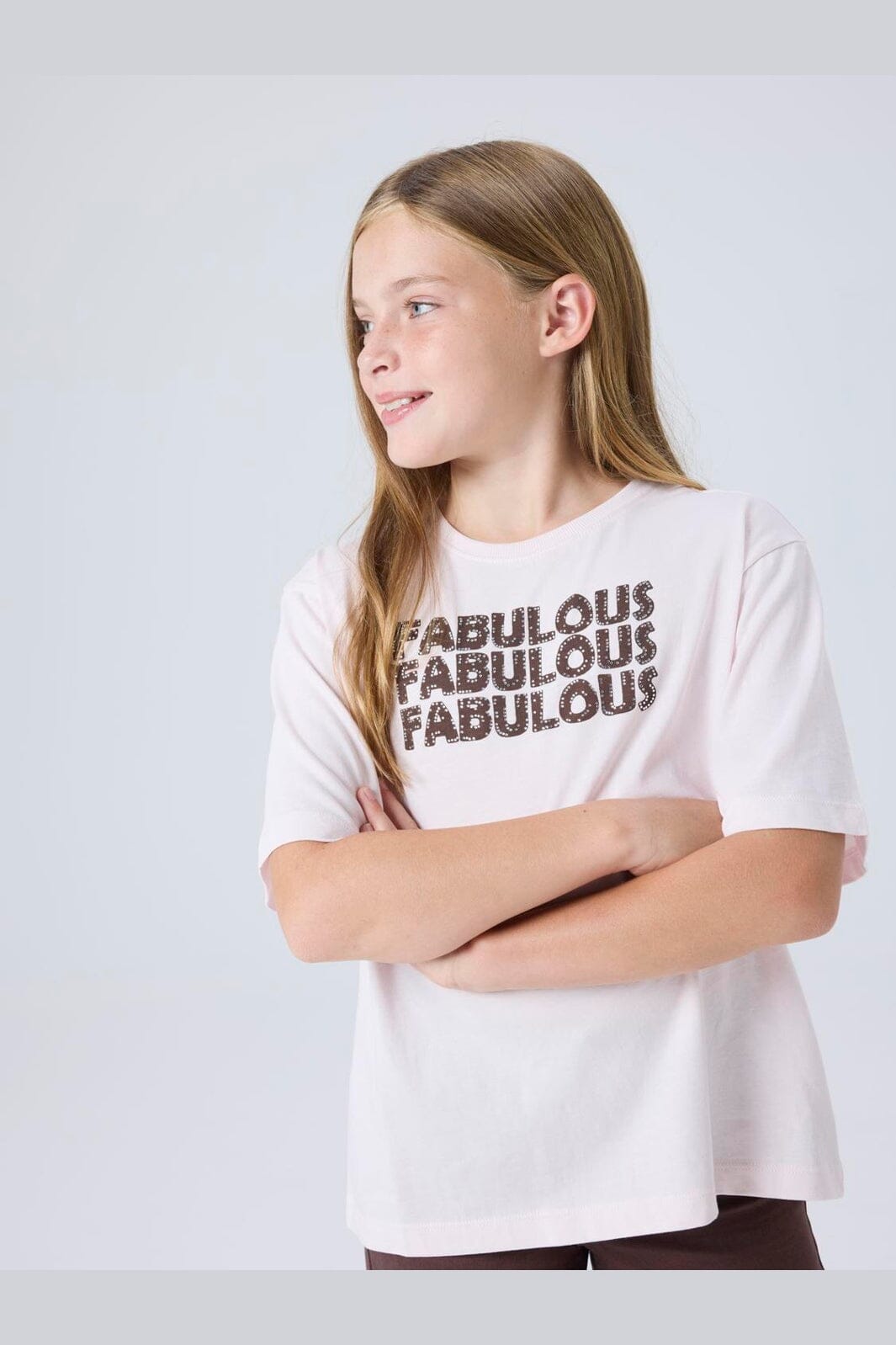 Young girl wearing a white t-shirt with 'FABULOUS' text on a light gray background