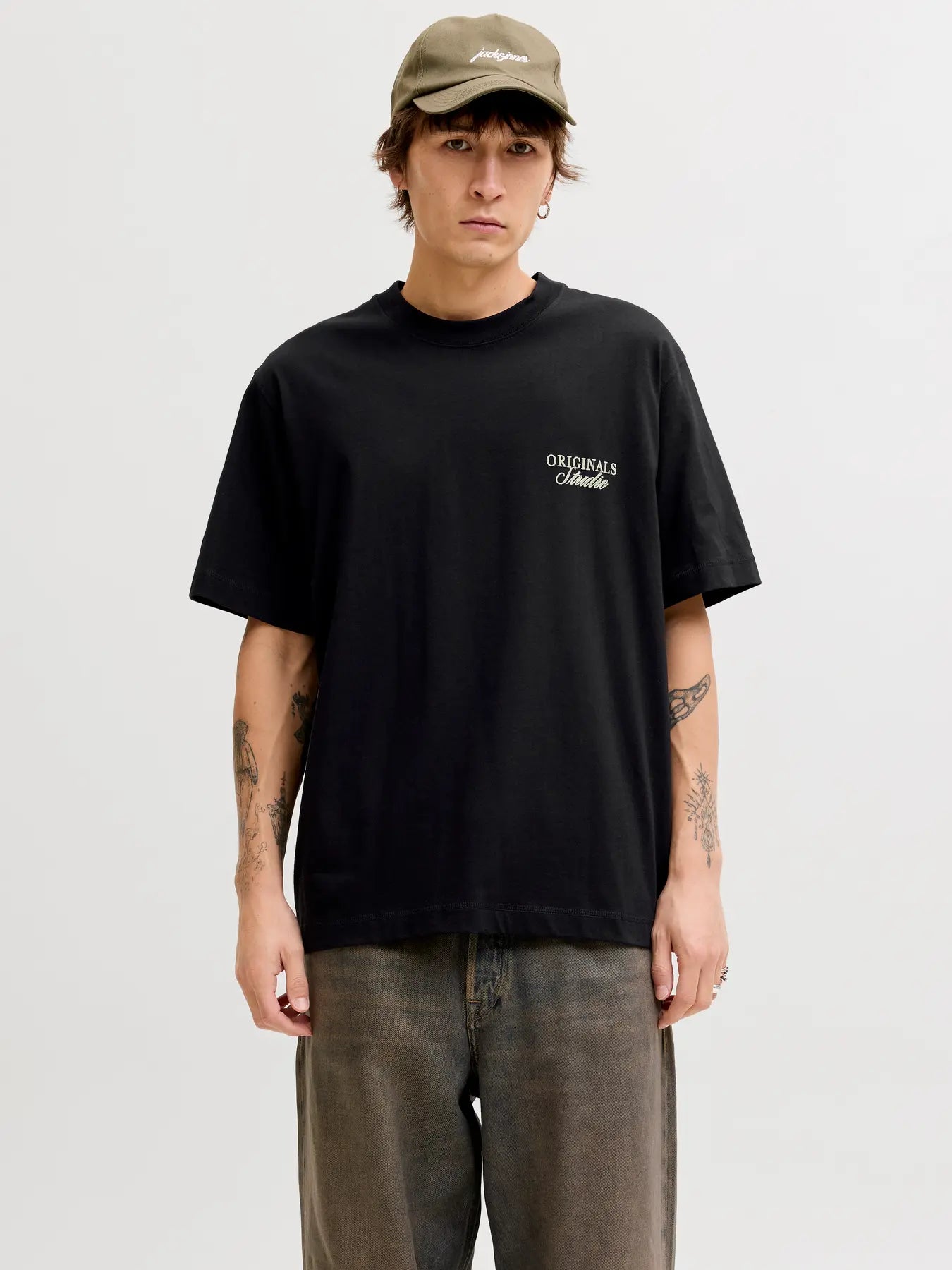 Person wearing a black t-shirt with a logo and a cap on a white background