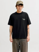 Person wearing a black t-shirt with a logo and a cap on a white background