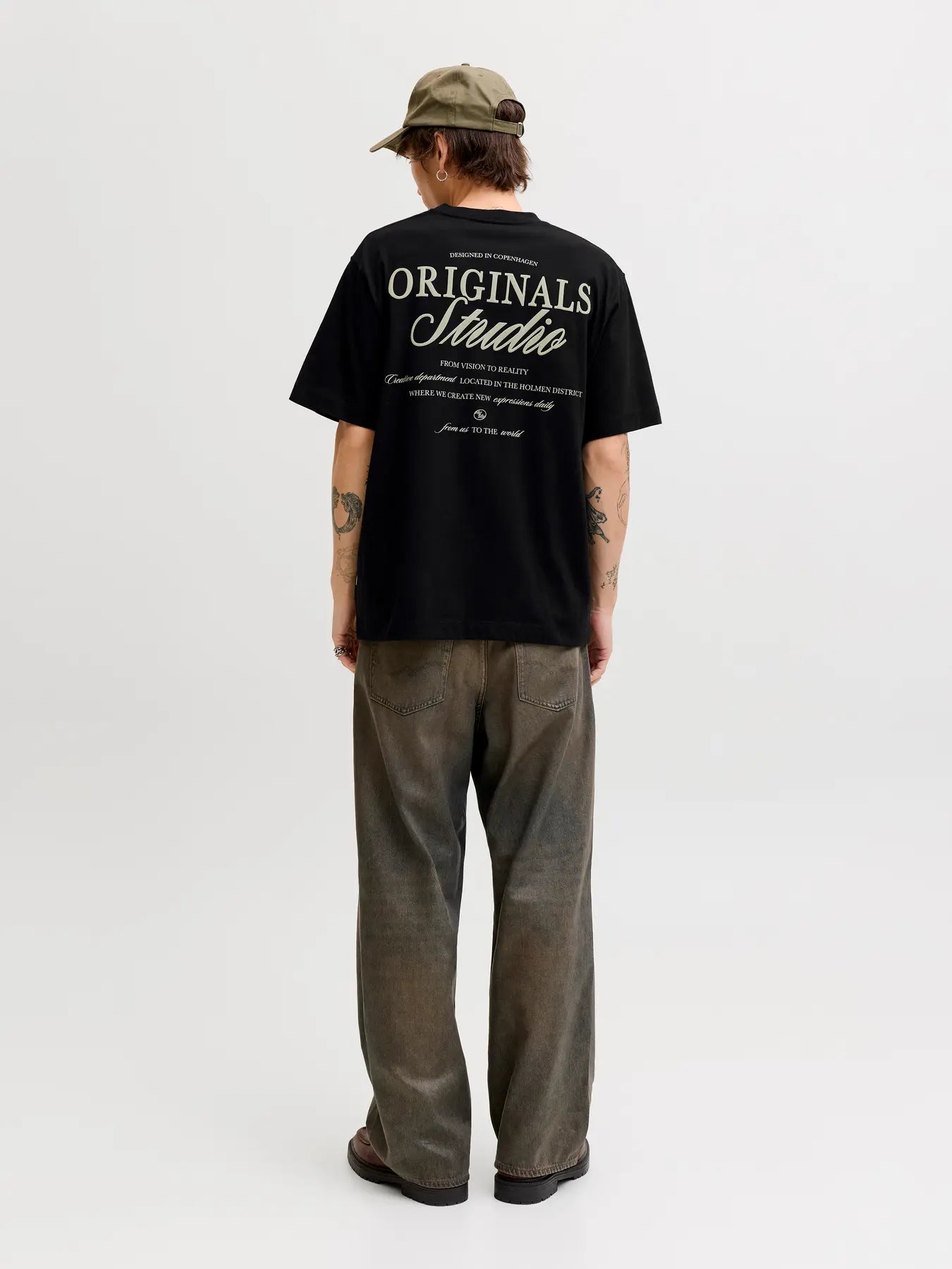 Person wearing a black 'Originals Studio' t-shirt on a white background