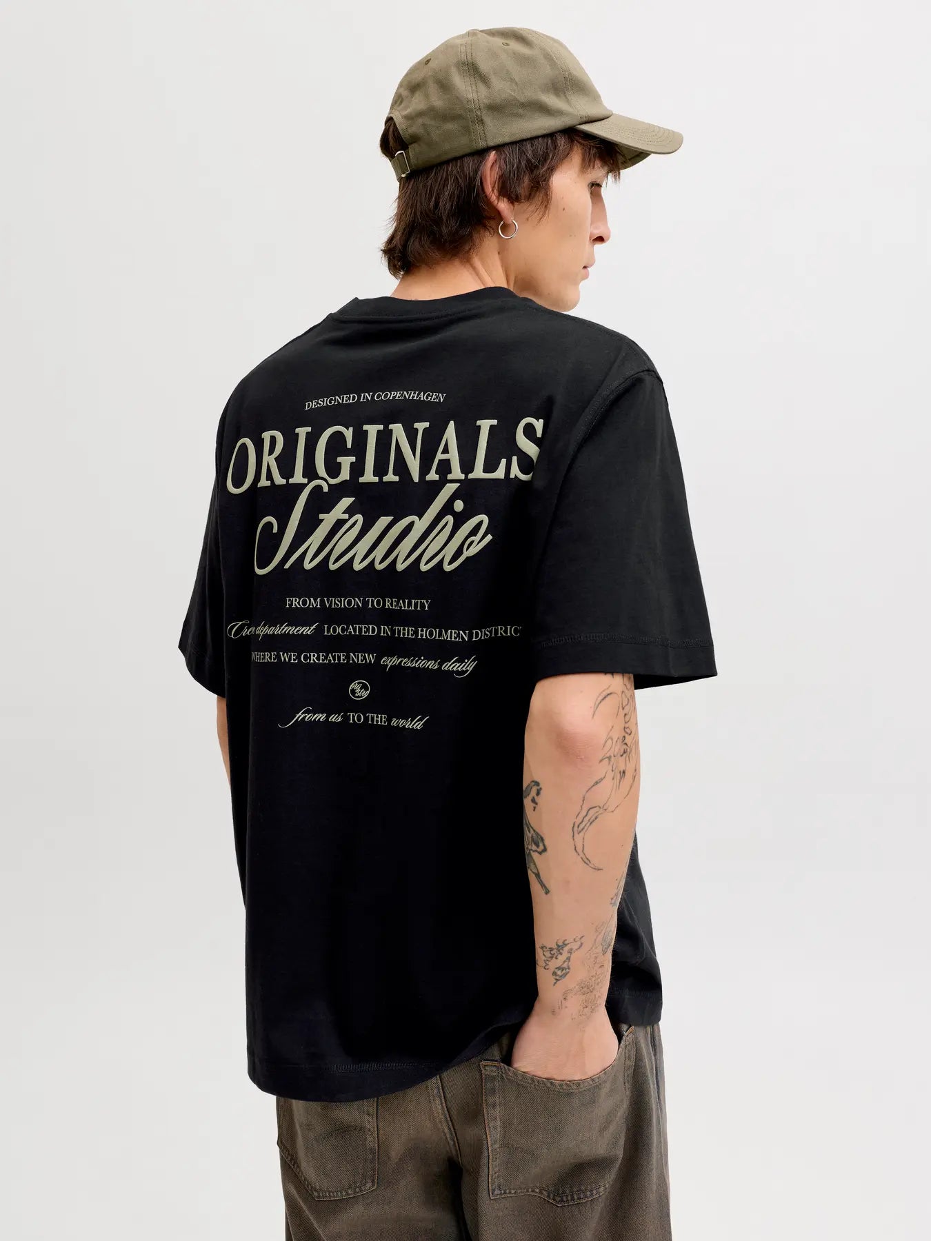 Person wearing a black t-shirt with 'Originals Studio' text on the back, standing against a plain background.