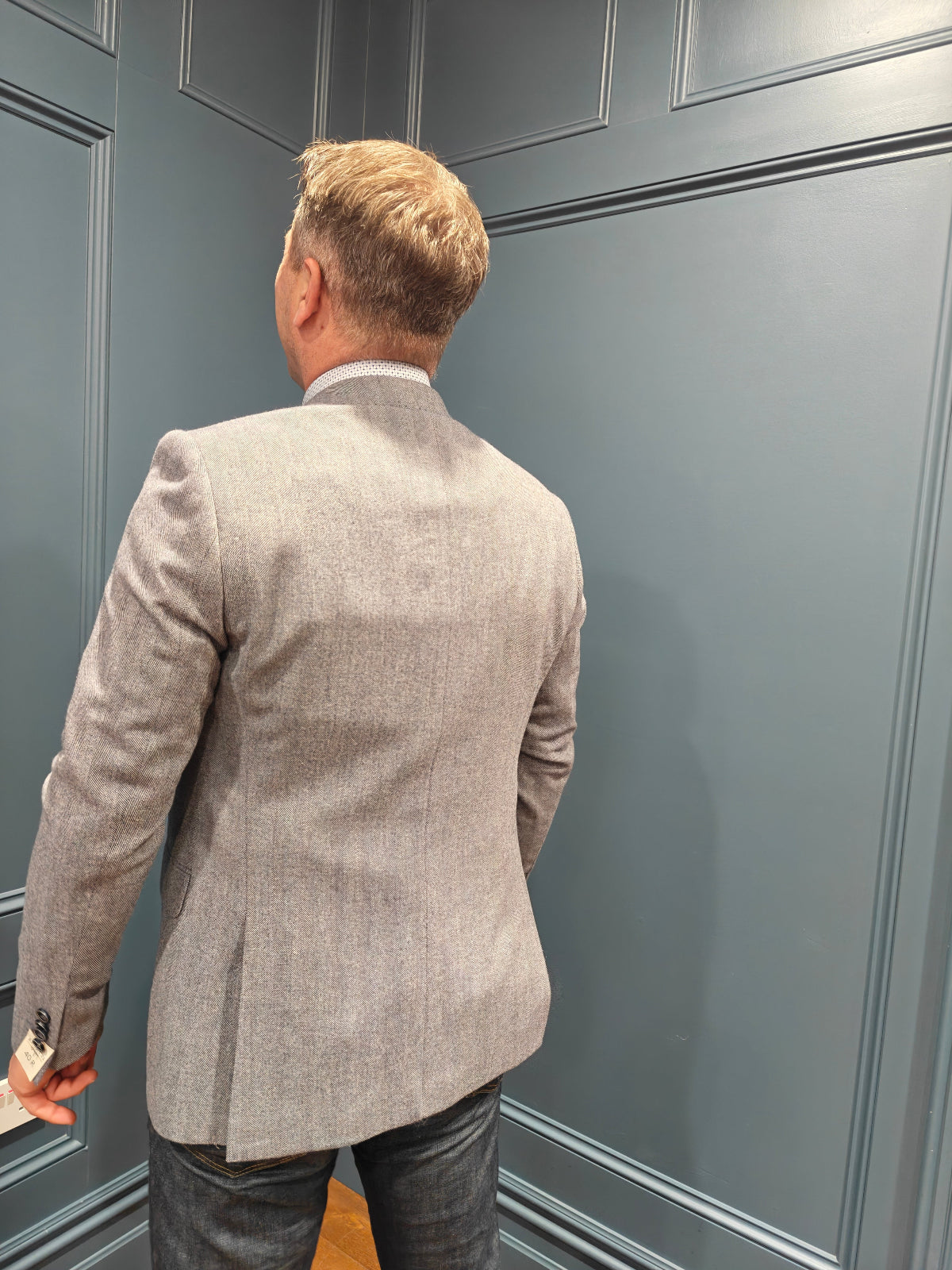 Man wearing a gray blazer against a gray paneled wall