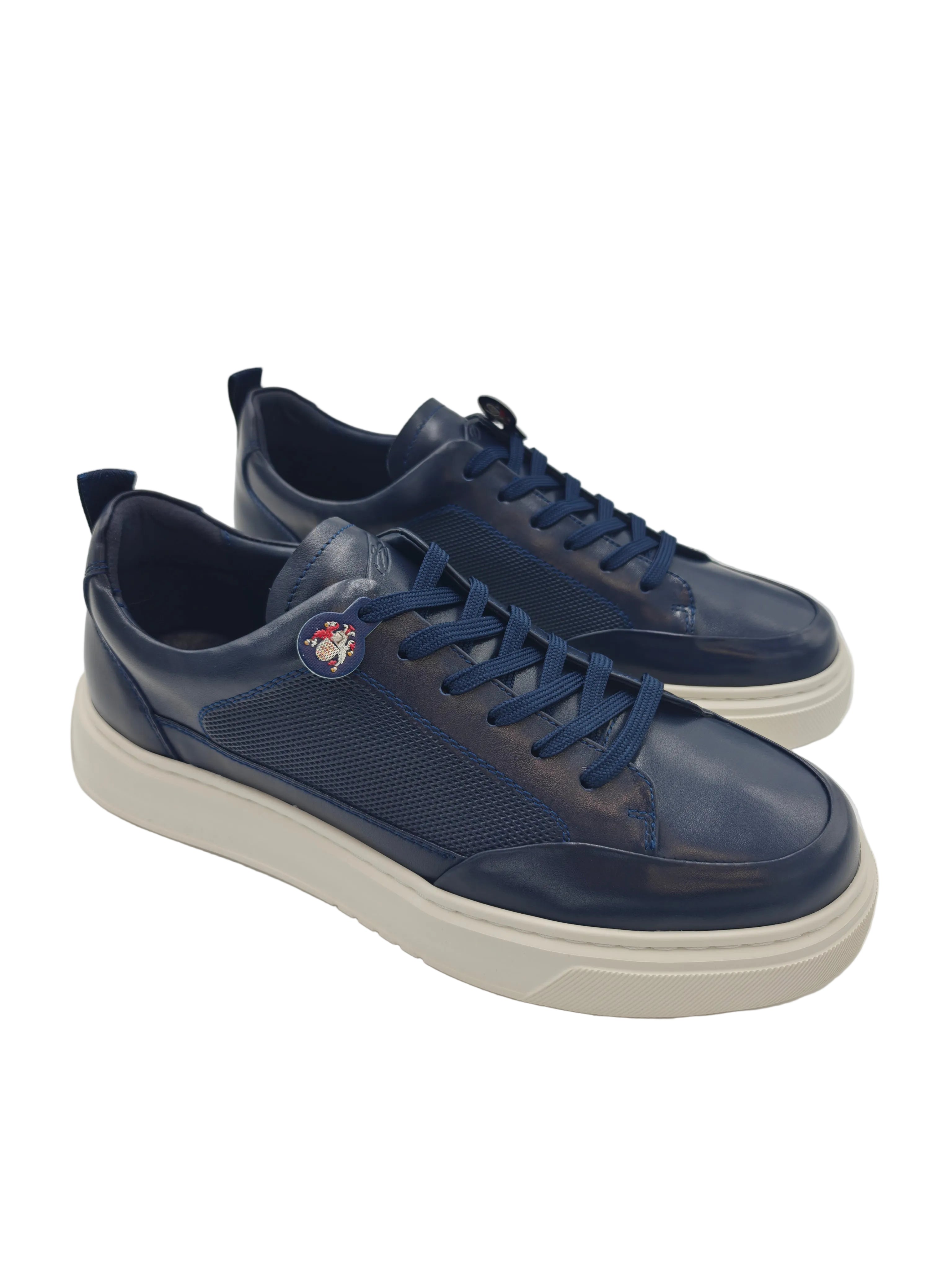 Pair of navy blue sneakers with a white sole on a reflective surface.
