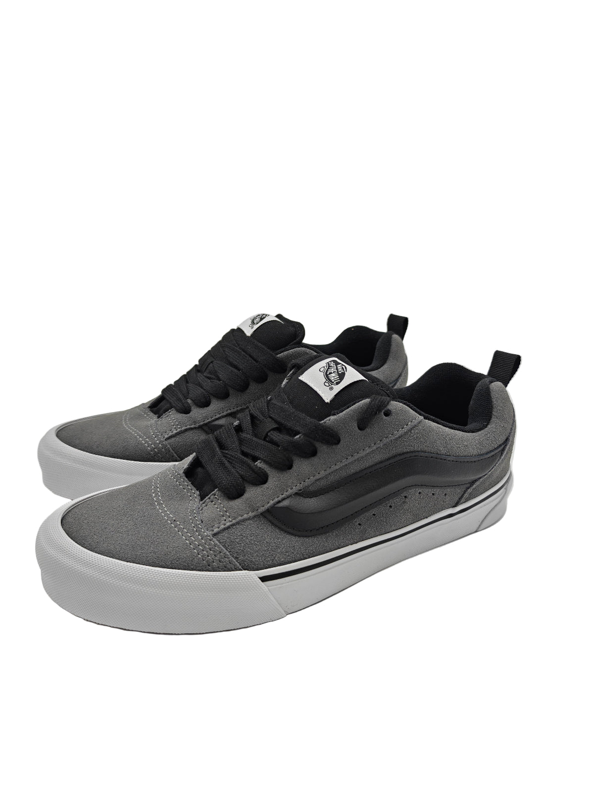 Gray sneakers with black laces on a white surface, with a reflective silver background.