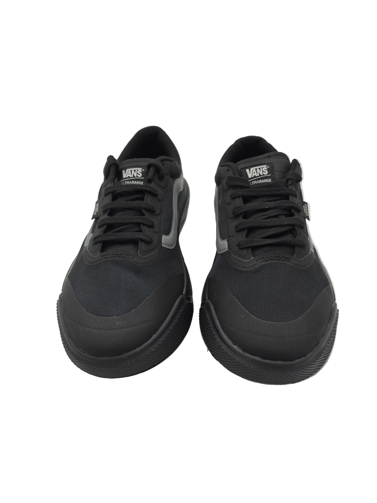 Black Vans sneakers on a white surface with a clear plastic bag in the background.