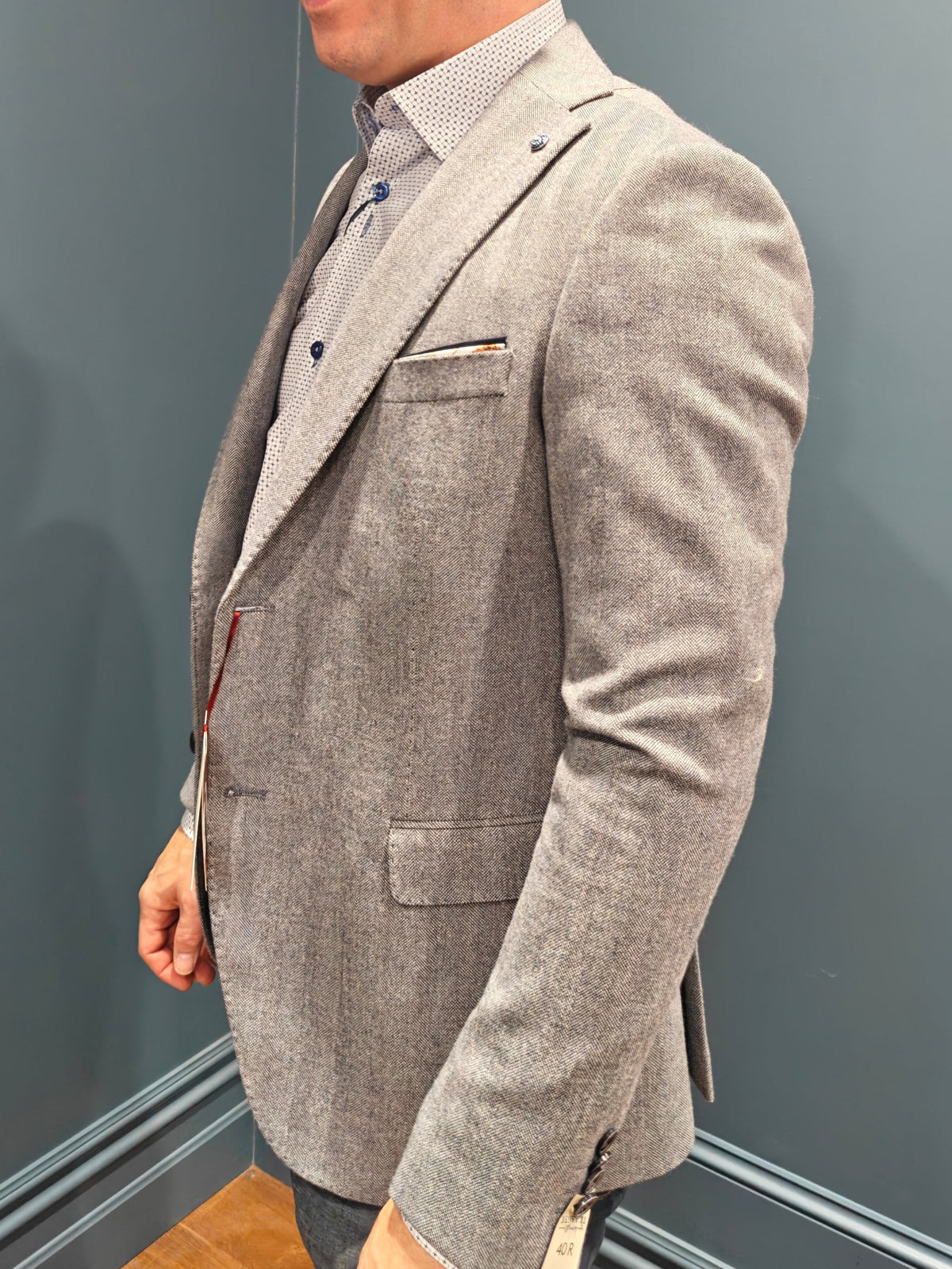 Man wearing a gray blazer against a gray paneled wall