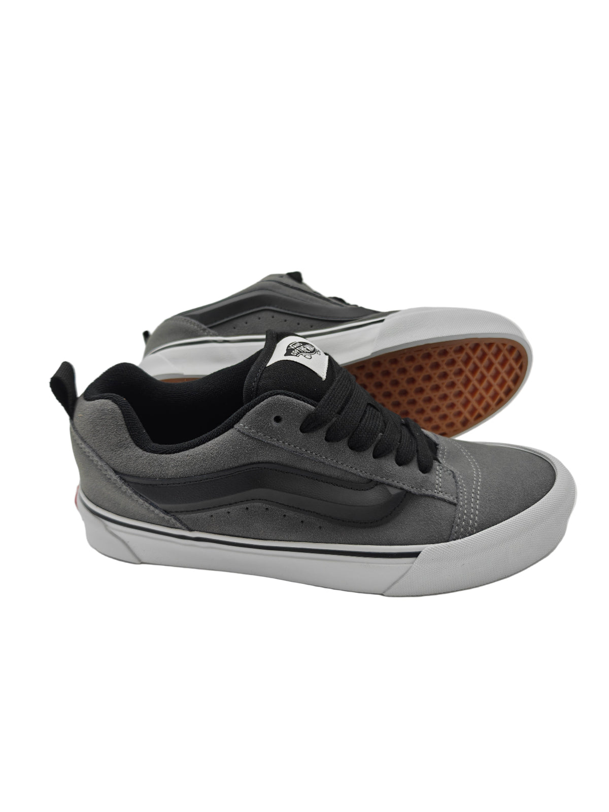 Gray sneakers with black laces on a white surface with a reflective background