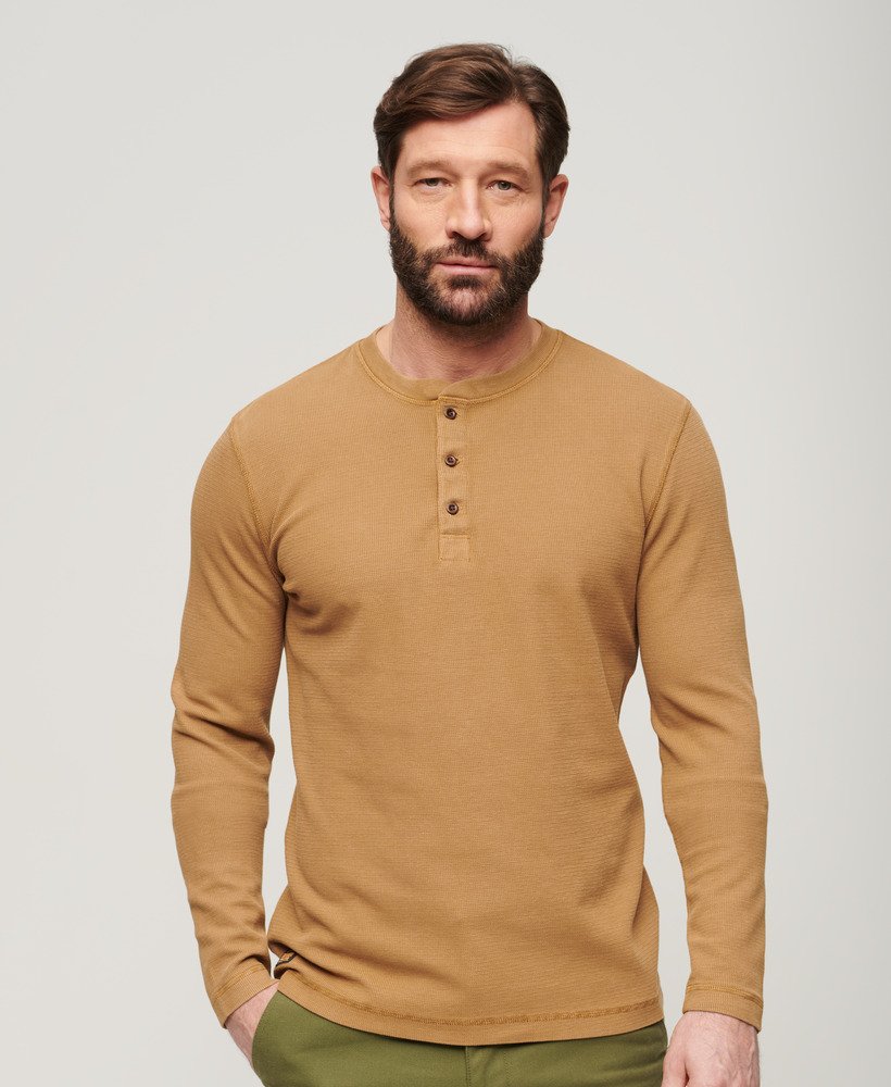 Man wearing a brown long-sleeve henley shirt against a plain background