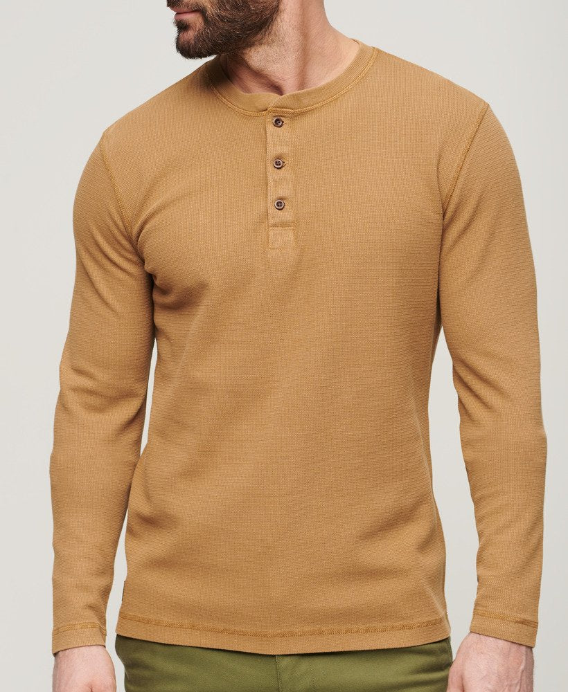 Man wearing a brown long-sleeve henley shirt against a plain background