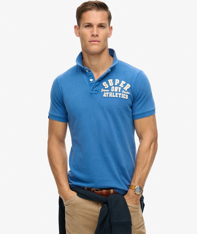 Man wearing a blue polo shirt with visible branding on a white background