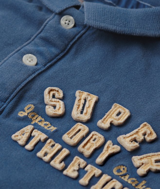 Close-up of a blue polo shirt with embroidered text on a blue background